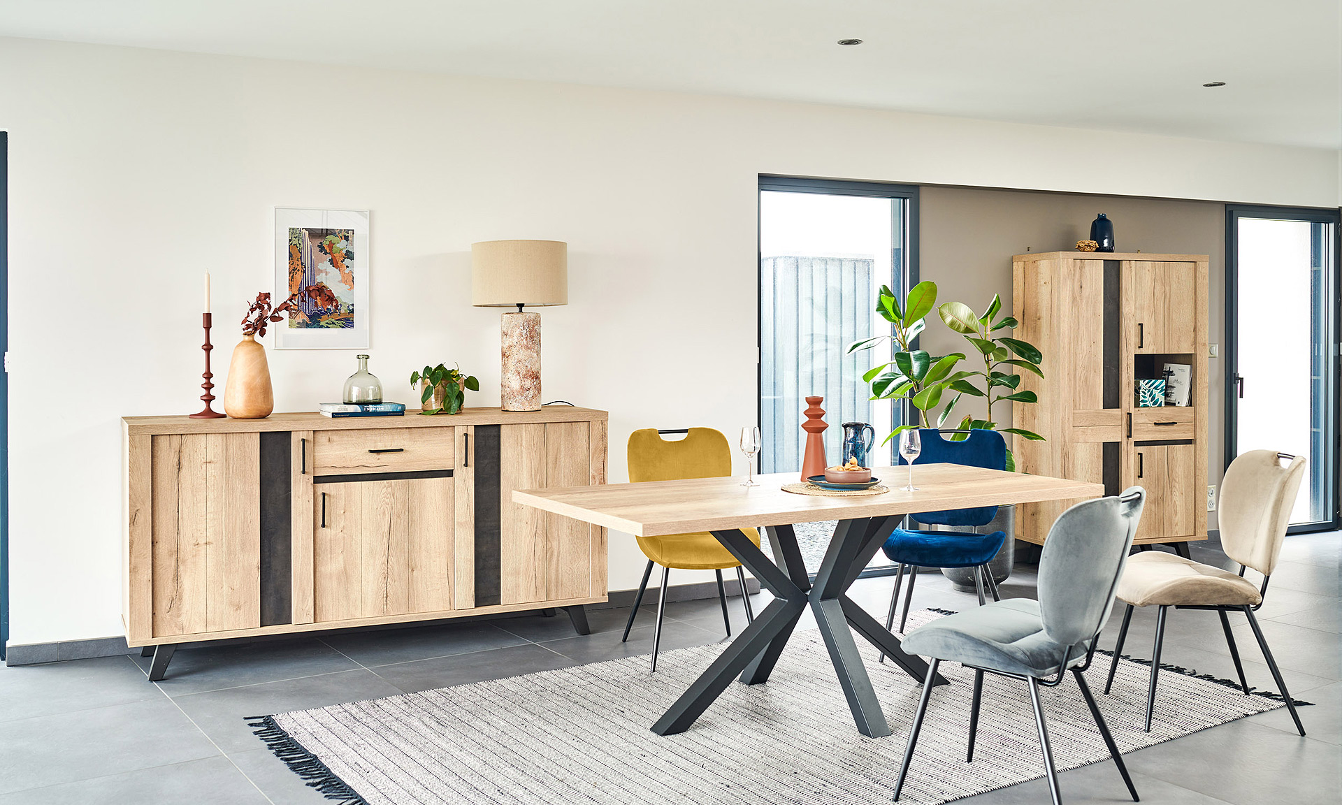 Photo d'une salle à manger avec une collection comprenant une enfilade, une table de repas, des chaises et un meuble de rangement. Les meubles présentent des finitions en chêne naturel style brut industriel et des piétements en métal noir.