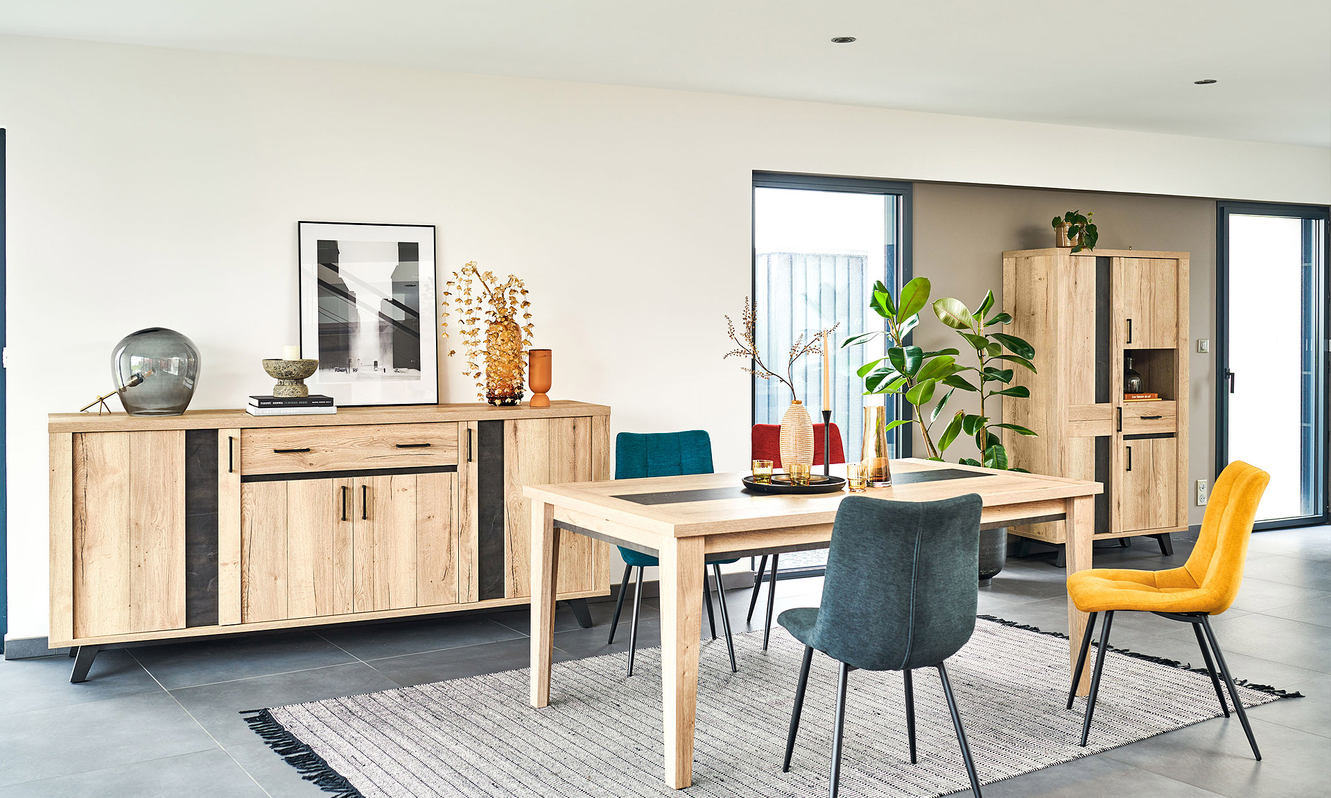 Photo d'une salle à manger avec une collection comprenant une enfilade, une table de repas, des chaises et un meuble de rangement. Les meubles présentent des finitions en chêne naturel style brut industriel et des piétements en métal noir.